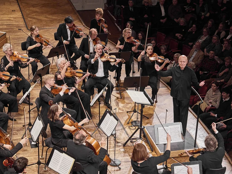 Paavo Järvi mit Die Deutsche Kammerphilharmonie Bremen: Ein Dirigent leitet ein großes Orchester vor einem Publikum. Die Musiker spielen Streich- und Blasinstrumente in einem Konzertsaal.