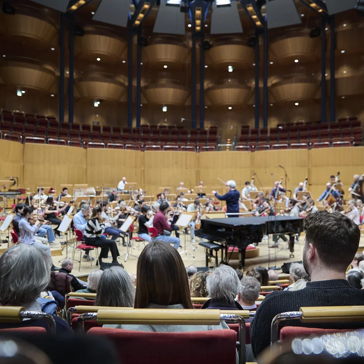 Ein Orchester spielt in der Kölner Philharmonie vor einem Publikum. Der Dirigent steht vor den Musikern.