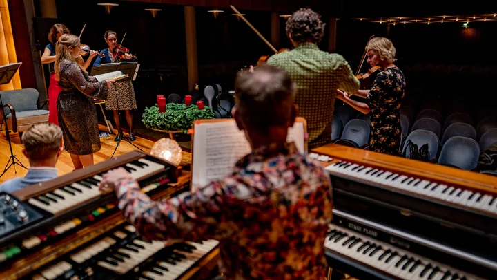 Ensemble Resonanz: Weihnachtsoratorium - Ein Orchester auf der Bühne mit Tasteninstrumenten im Vordergrund und Streichinstrumenten im Hintergrund. Die Musiker proben konzentriert.