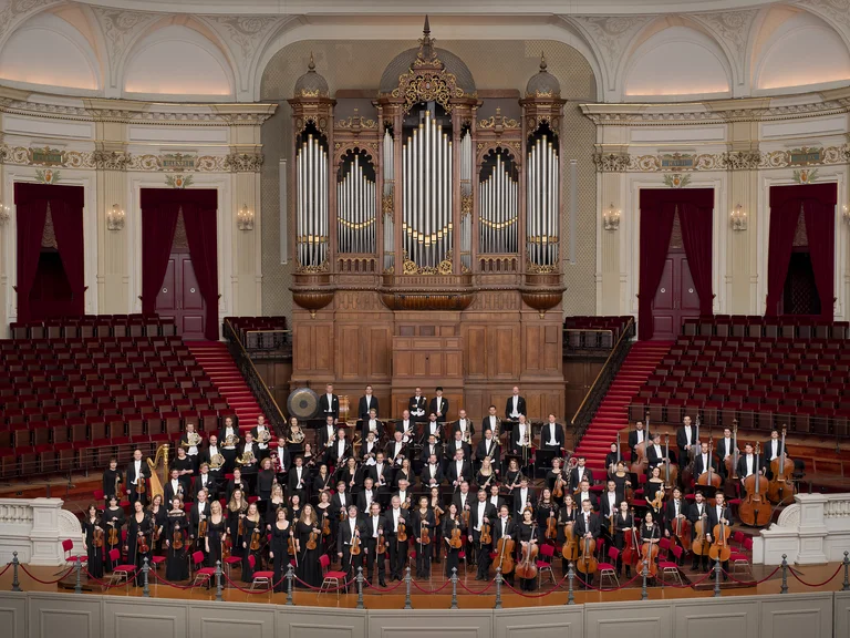 Royal Concertgebouw Orchestra: Ein Symphonieorchester auf einer großen Bühne in einem Konzertsaal. Im Hintergrund ist eine beeindruckende Orgel zu sehen.